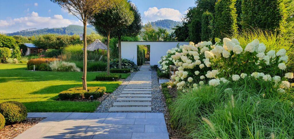 Gartenweg mit weißen Blüten und moderner Landschaftsgestaltung