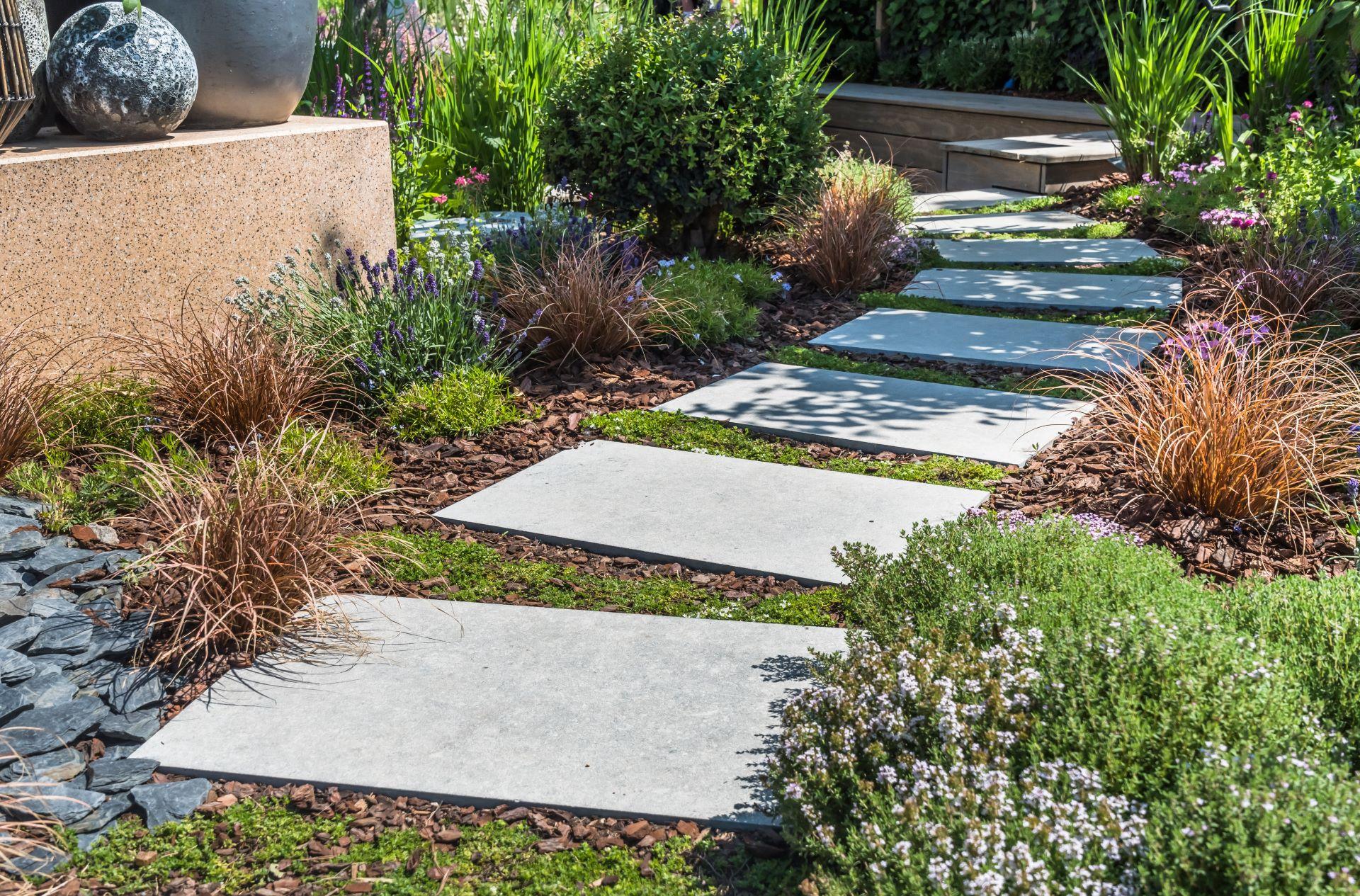 Natursteinplatten mit Bepflanzung in moderner Gartenlandschaft